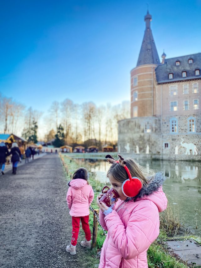 girl drinking hot chocolate at a christmas market in front of a castle in merode